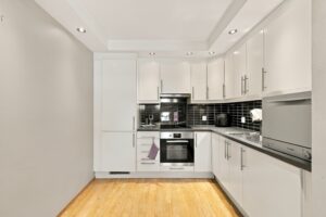 Moderne Ikea kjøkken fra 2010 med glatte fronter og benkeplate med laminert overflate. Her er det integrert stekeovn, platetopp og kjøleskap med fryser samt frittstående oppvaskmaskin.