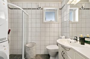 Utleiedelen har eget bad med flislagte gulv og vegger. Badet er innredet med servant, toalett og dusjhjørne med glassdører, elektrisk avtrekksvifte samt opplegg for vaskemaskin.