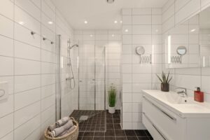 Helfliset bad/wc/vaskerom som har en tidløs stil. Moderne innredning, vegghengt toalett med innebygget sisterne og romslig dusjhjørne med innfellbare glassvegger.