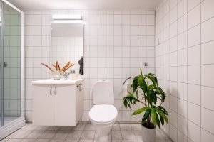 Badet lyst med fliser på gulv og baderomsplater på vegg. 