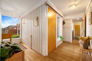 Gang/entré med parkett på gulv og panel på vegger. 