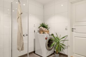 Funksjonelt bad med romslig dusjløsning og opplegg for vaskemaskin.
