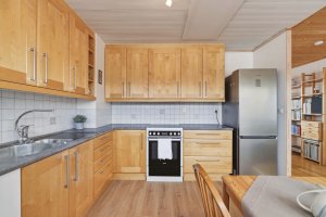 Kjøkkeninnredningen fra Mørekjøkken (2006) har profilerte bjørkefronter og takhøy løsning som gir godt med oppbevaringsplass.