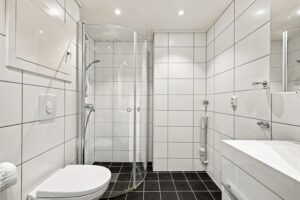 Badet har dusj med foldedører i herdet glass.