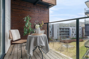 Terrassen har trykkimpregnerte terrassebord og høyt rekkverk i glass og metall