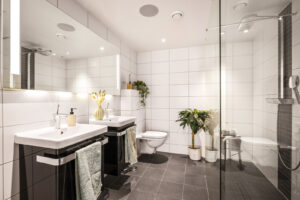 Badet inneholder dobbel servant med møblement/speil og belysning,
vegghengt toalett, dusjvegg i glass, innfelbar dusjdør i glass,
og dusjgarnityr.