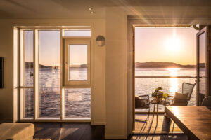 Et majestetisk rom hvor lyset og de fine fargene fra sjøen flommer inn i stuen.