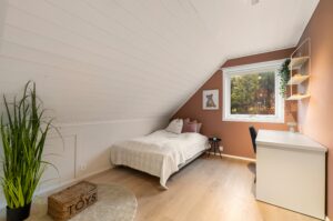 Romslig soverom med plass til både seng og oppbevaring, malt i en frisk fargepalett.