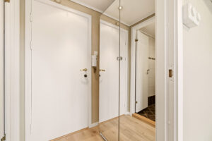 Lys og trivelig entré med porttelefon og garderobeskap med speilfronter, som skaper en positiv romfølelse.