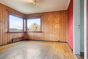 Vegg-i-vegg med spisestuen finner man boligens dagligstue med originalt furugulv og panel på de fleste overflatene. 