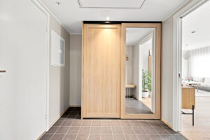 Lys og trivelig gang med moderne gulvfliser samt praktisk garderobe med eikefronter og speilglass. 